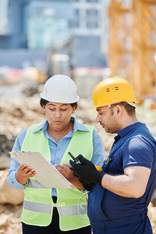 Safety professionals in hard hats reviewing a workplace plan on site